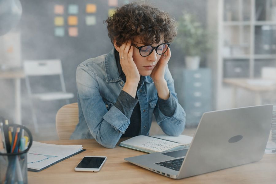Person experiencing brain fog and stress while working at laptop